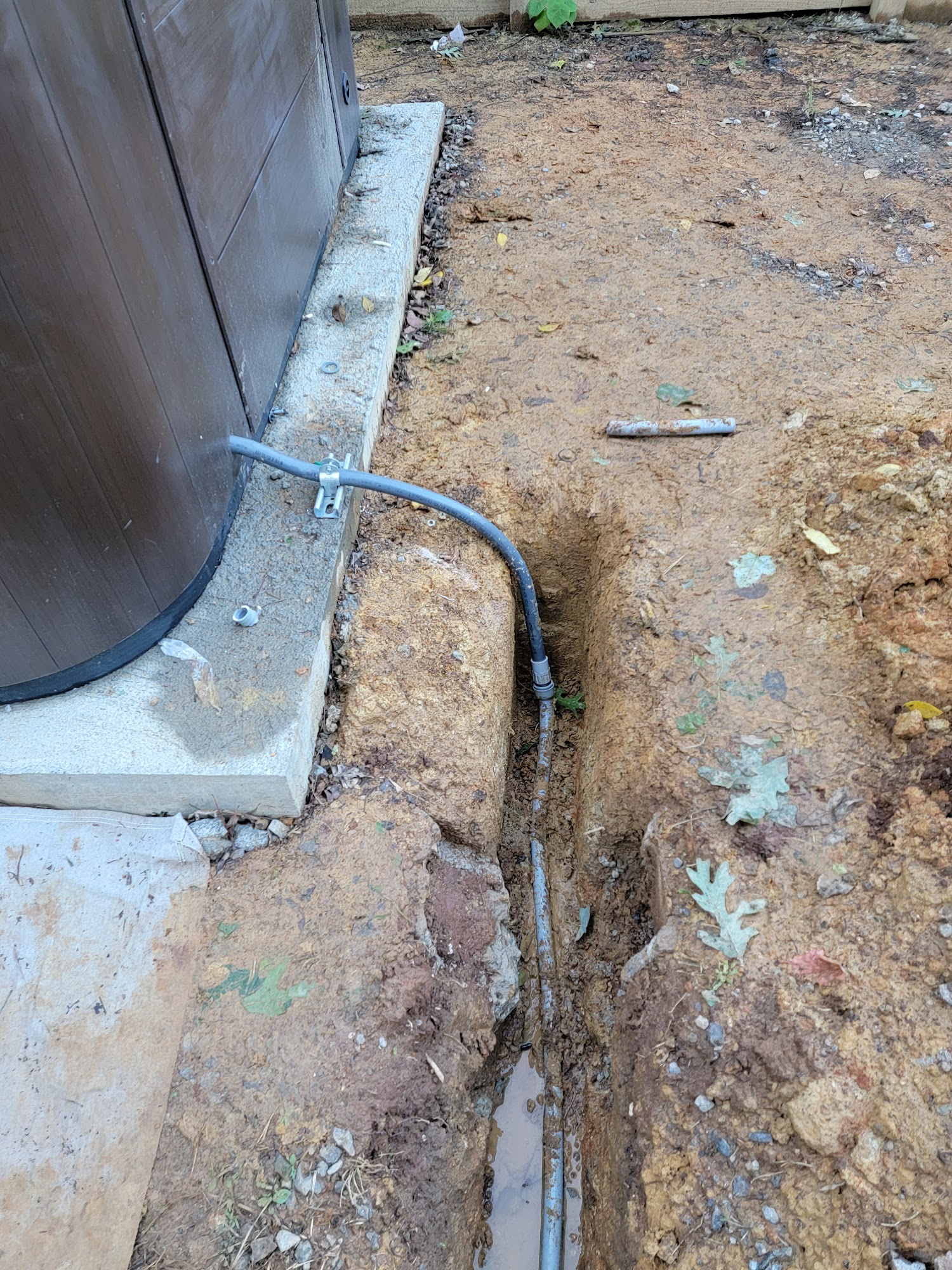 Outdoor wiring work beside a home's foundation